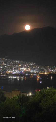a full moon rising over a city at night at The suite in Eilat