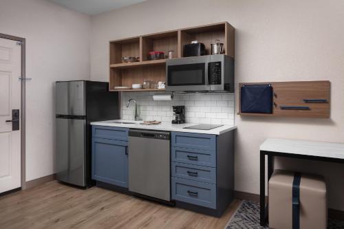 a kitchen with blue cabinets and a refrigerator at Candlewood Suites St. Robert by IHG in Saint Robert