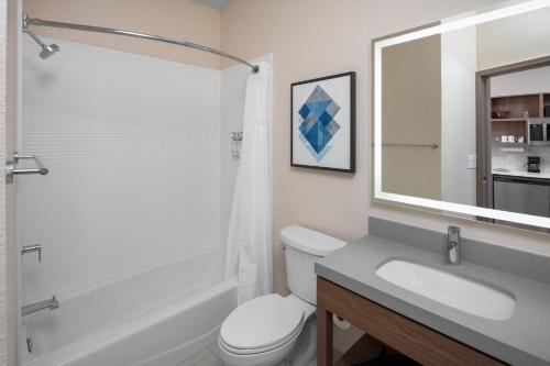a bathroom with a sink and a toilet and a mirror at Candlewood Suites St. Robert by IHG in Saint Robert
