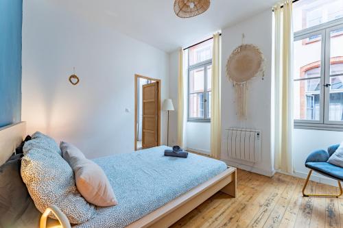 a bedroom with a bed and a chair and windows at Le beau Malcousinat place Nationale wifi haut débit in Montauban