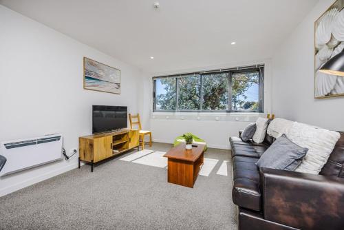 a living room with a couch and a television at Eden Vista 3 bedroom Apartment with free parking in Auckland