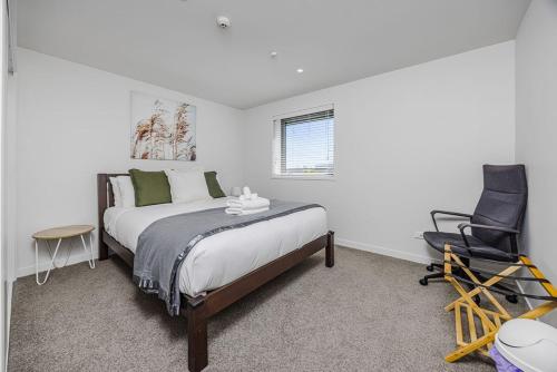 a bedroom with a bed and a chair in it at Eden Vista 3 bedroom Apartment with free parking in Auckland
