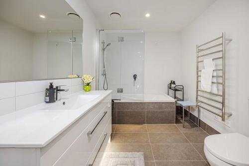 a white bathroom with a tub and a toilet at Eden Vista 3 bedroom Apartment with free parking in Auckland