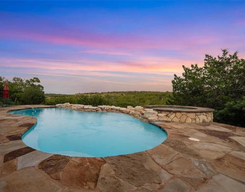 a large swimming pool with a stone patio at Hilltop Saltwater Pool and Hot Tub in Dripping Springs