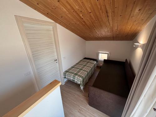 a small bedroom with a bed and a wooden ceiling at Flamingo Apartment in Pachino