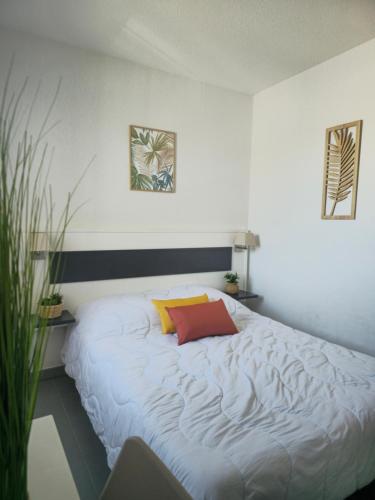 a bedroom with a white bed with a red pillow at Apartment 4-6 personnes avec Piscine Demeure De la Massane in Argelès-sur-Mer