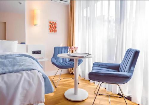 a bedroom with two blue chairs and a table and a bed at ORBI CITY LUXURY deluxe KIG DVD in Batumi