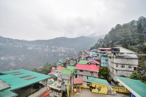 a group of buildings with mountains in the background at Hotel O Parasol Inn Gangtok in Gangtok