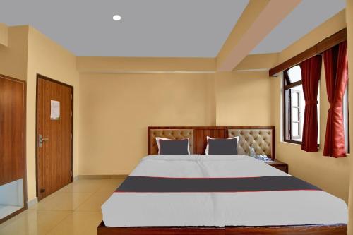 a bedroom with a large bed and a window at Hotel O Parasol Inn Gangtok in Gangtok