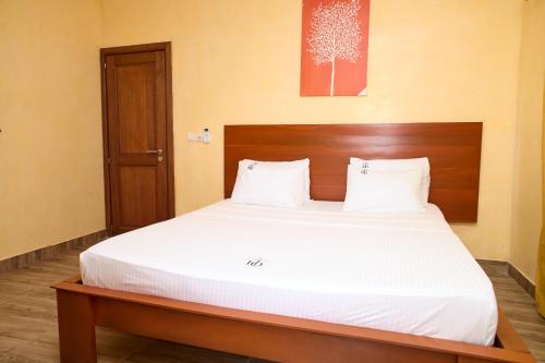 a bedroom with a large white bed with a wooden headboard at Résidence HQ in Brazzaville