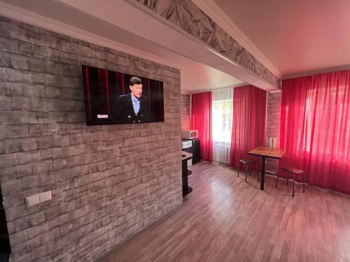 a living room with a tv on a brick wall at Вип Квартира посуточно in Shakhtīnsk