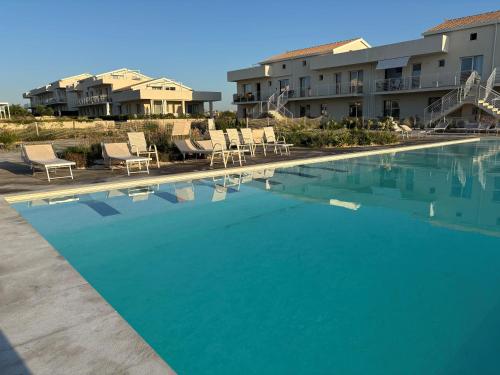 a large blue swimming pool with chairs and condos at Flamingo Apartment in Pachino