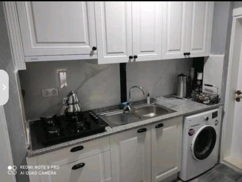 a kitchen with white cabinets and a sink and a dishwasher at mila's home in Seferihisar