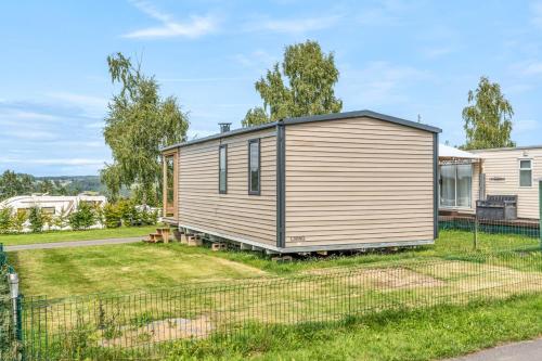 a tiny house in a yard with a fence at Maison de Vacances - Parc de Vacances Papillon Bouillon in Bouillon