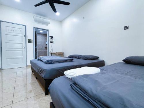 a bedroom with two beds and a ceiling fan at MiuMiu Homestay in Teluk Intan