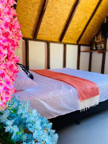 un letto con una coperta rossa e fiori blu di Hotel Cabañas Villa Loe Jardín a Jardin