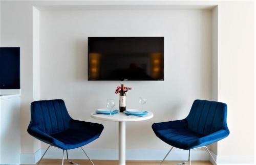 two blue chairs and a table with a vase of flowers at Glorious Sea View Aparthotel In Orbi City Batumi in Batumi