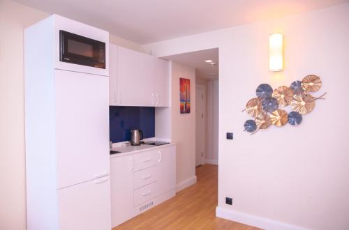 a kitchen with white cabinets and a tv on the wall at Glorious Sea View Aparthotel In Orbi City Batumi in Batumi