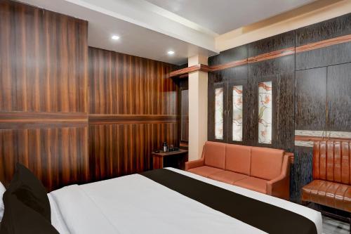 a hotel room with a bed and a chair at Super Collection O Patliputra Sports Complex Formerly Wellfood Inn in Patna