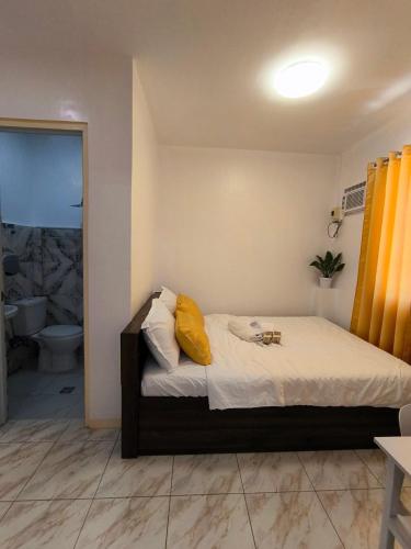a bedroom with a bed with a yellow pillow on it at AMS Apartment in Butuan