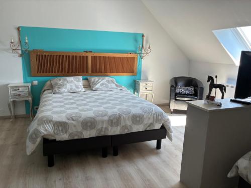 a bedroom with a bed with a blue headboard and a desk at B&B Haras de la Cour Fleury in Saint-Michel-de-Livet