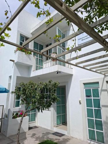 a white house with green windows and a balcony at Milenio III B&B in Querétaro