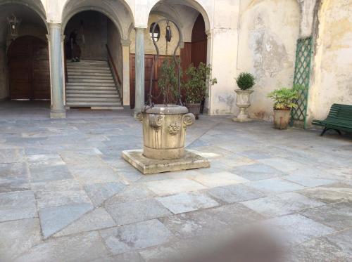 a stone courtyard with a vase with plants in it at B&B Del Piazzo in Biella