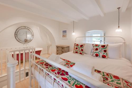 a white bedroom with a bed and a mirror at The Triumphal Arch East in Holkham