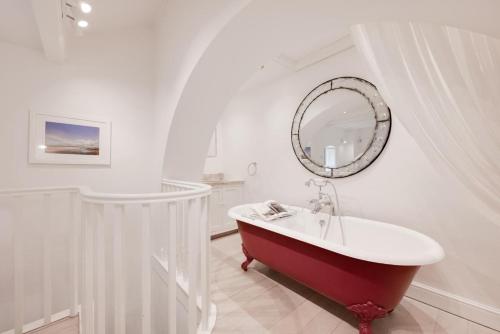 a bathroom with a red bath tub and a mirror at The Triumphal Arch East in Holkham