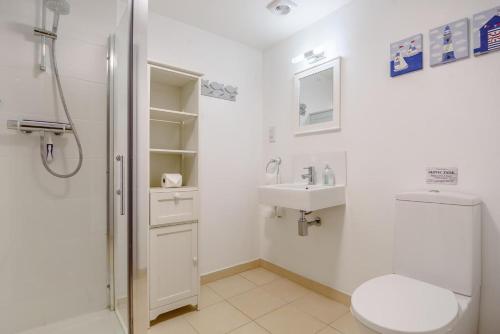 a bathroom with a toilet and a sink and a shower at Vine Cottage in West Runton