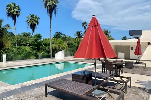 ein Swimmingpool mit einem roten Sonnenschirm und Stühlen und einem Tisch und einer Tischplatte in der Unterkunft 506 Plaza 3.14 by Del Mar in Nuevo Vallarta