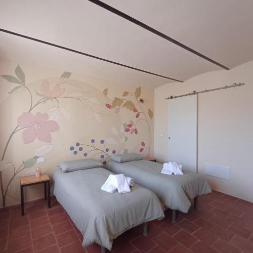 two beds in a room with flowers on the wall at B&B La RU in Montemagno