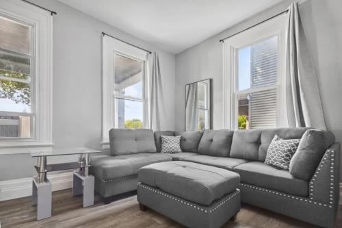 a living room with a couch and a table and windows at 5BR Home-Walk to Niagara Falls & Aquarium in Niagara Falls