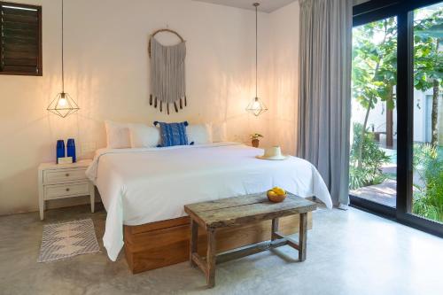a bedroom with a large white bed and a table at La Zebra Tulum, a Small Luxury Hotel in Tulum