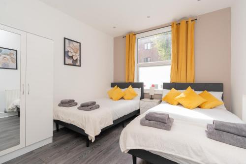 Dos camas en una habitación con ventana. en Open Mind Property - Stylish 4BR House with 7 Beds, en Portsmouth