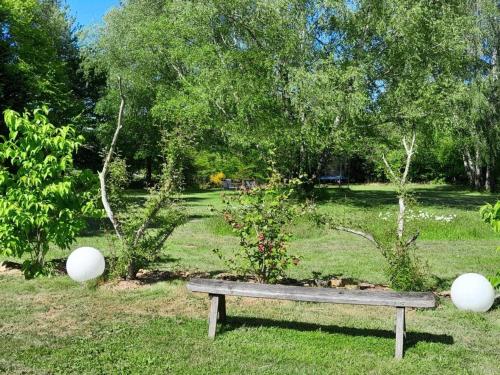 a park bench sitting in the grass in a park at Gîte de France C'est tout vert 4 épis - Gîte de France 5 personnes MAE-9824 in Condat-sur-Ganaveix