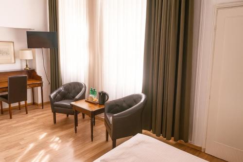 Una habitación de hotel con una cama, una mesa y sillas. en HOTEL Am Ratshof, en Halle an der Saale