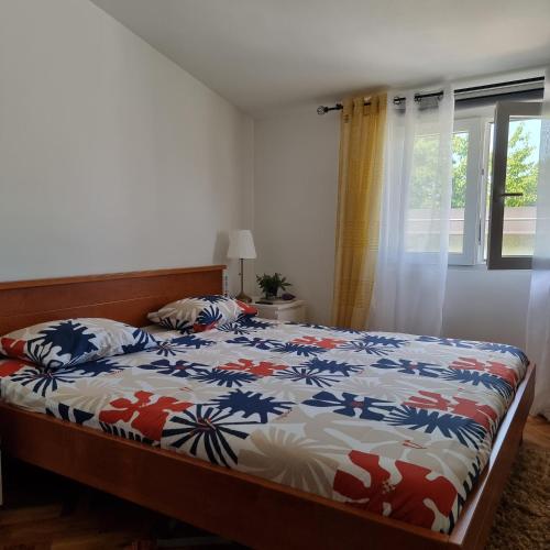 a bedroom with a bed with a colorful comforter and a window at Indigo Dreams in Ogulin