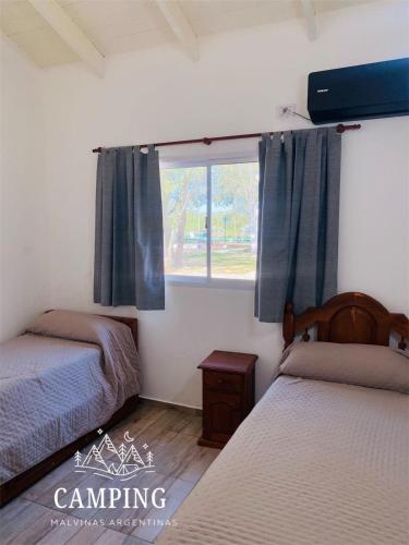 a bedroom with two beds and a window at Cabañas Camping Malvinas Argentinas in Paso de la Patria