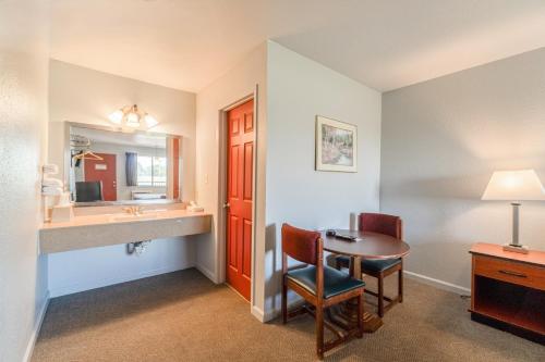 a hotel room with a desk and a table and a sink at Capital O Aurora Inn Monett US 60 in Aurora
