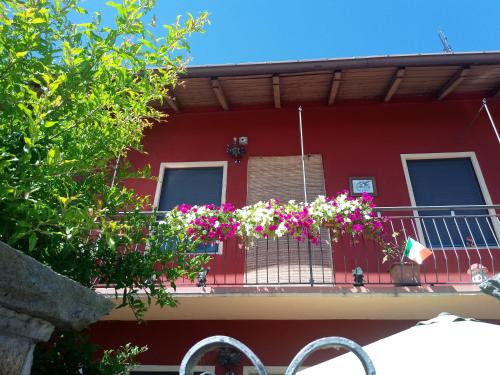 a red house with a balcony with flowers on it at La casa dei poeti in Cervasca
