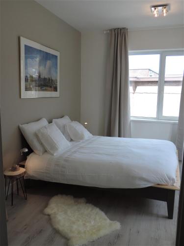 a bedroom with a large white bed with a window at Sea & Dunes in Scheveningen