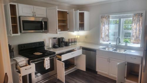 a kitchen with white cabinets and a stove and a sink at 83rd Street Comfy Cottage in Irondale