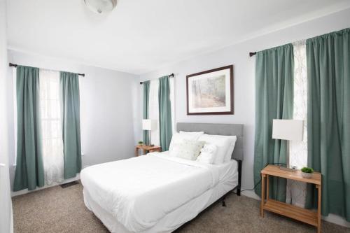 a bedroom with a large white bed with green curtains at 4th St Little Blue in Bham in Graymont
