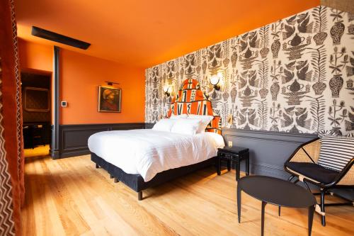 a bedroom with a bed with an orange wall at Hôtel La Particulière in Caen