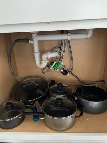 four pots and pans under a kitchen sink with a pipe at 47th Place Forest Park in Mountain Brook