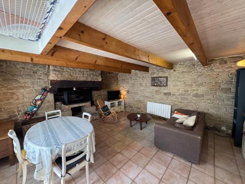 a living room with a table and a stone wall at Charmant penty avec cheminée in Sainte-Hélène