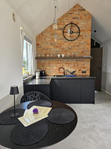 a kitchen with a black table and a brick wall at BOSKO domki z sauną i balią w Sulminie obok Gdańska in Sulmin