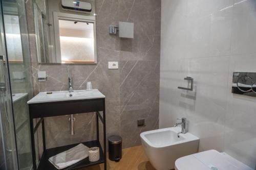 a bathroom with a sink and a toilet and a mirror at Flat Urban Suites in Rome