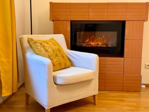 ミュンヘンにあるModernes Zimmer am Park mit Garten, Hühner & Entenの暖炉の前にある枕付きの白い椅子